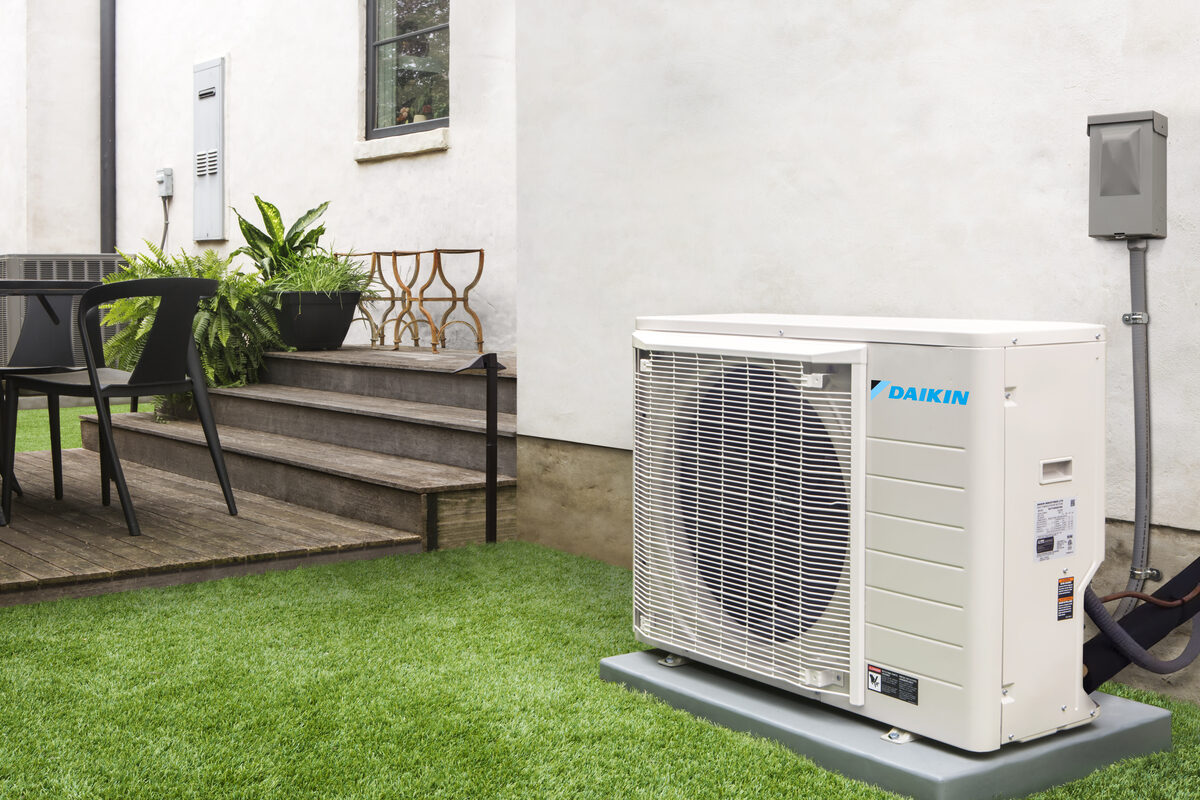 Green grass lawn beside a home with a heating unit on it